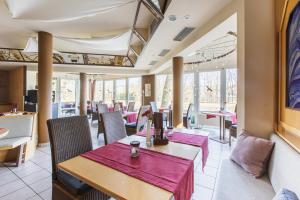 un comedor con mesas, sillas y ventanas en WAGNERS Seehotel Schleusingen en Schleusingen