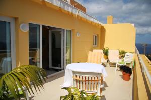 une terrasse avec une table et des chaises sur un balcon dans l'établissement Villa Erika Madeira -Penthaus-, à Caniço
