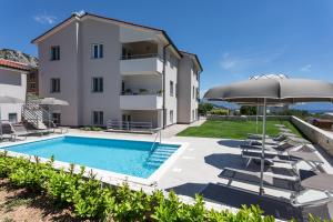 een villa met een zwembad en een parasol bij Apartments Mateo in Baška