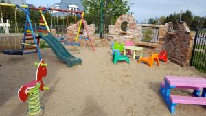 a playground with colorful play equipment in the sand at Domki U Ali w Rewalu in Rewal