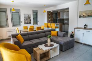 een woonkamer met een grijze bank en gele stoelen bij BUZUKU Apartments Liman (Mediterraneo) in Ulcinj