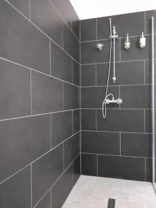 a black bathroom with a shower with black tiles at ESCAPADE AU COEUR DE LA RIVIERA BRETONNE in La Forêt-Fouesnant