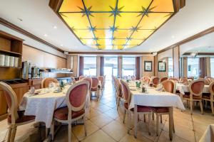 un restaurant avec des tables et des chaises et un plafond jaune dans l'établissement Hotel Des Tilleuls, à Dinard