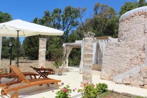 un patio con due sedie e un ombrellone di Trullo Le Macchie a Torre Suda