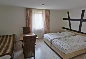 1 Schlafzimmer mit 2 Betten, einem Tisch und einem Stuhl in der Unterkunft Zum Schwarzen Adler in Mainberg