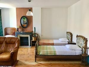 two beds in a room with a couch and a fireplace at Orfenor in Brioude