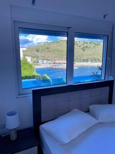 una camera da letto con due finestre con vista sull'acqua di Fabeno Villa a Sarandë