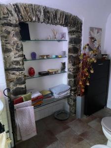 a bathroom with a stone wall with shelves and a toilet at La Casina Di Jessica in Aulla