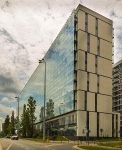 wysoki budynek ze szklanymi oknami na ulicy w obiekcie Apartamenty Prymasa Residence w Warszawie