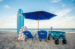 a beach chair and umbrella sitting on the beach at Beachside Hotel and Suites in Cocoa Beach