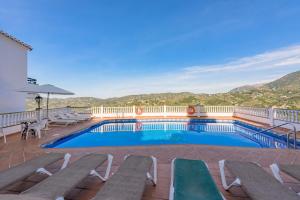 a swimming pool with benches and a view of the mountains at Apartamentos Rosamarina in Frigiliana