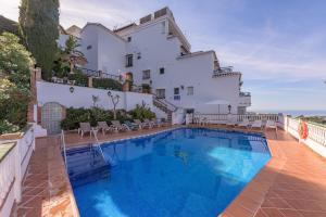 a villa with a swimming pool in front of a building at Apartamentos Rosamarina in Frigiliana