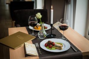 einen Tisch mit zwei Teller mit Speisen und Weingläsern in der Unterkunft AM Hotel Kaštieľ & Restaurant in Rimavská Sobota