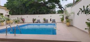 a large swimming pool next to a white wall at Presken Residence Annex in Ikeja