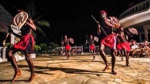 a group of men performing a tribal dance at night at Papillon Lagoon Reef Hotel in Diani Beach