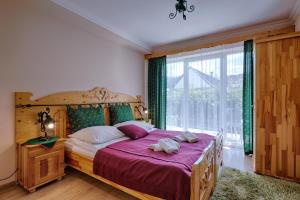 a bedroom with a wooden bed with a large window at Pensjonat Dawidek in Zakopane