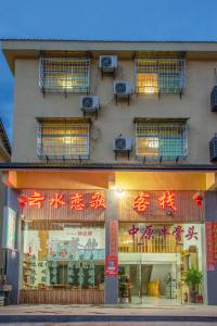 un bâtiment avec des panneaux de néon sur son côté dans l'établissement Nanjing Yunshuiyao Haixi Inn Dashuiche, à Nanjing