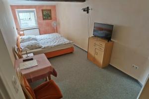 a small bedroom with a bed and a television at Zum Schwarzen Adler in Mainberg