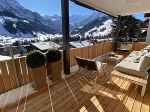 a deck with a couch and chairs on a balcony with mountains at Apartment Alpenrose by Interhome in Adelboden