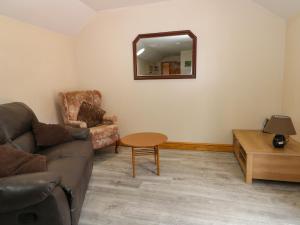 een woonkamer met een bank, een stoel en een spiegel bij Honeybee Cottage in Hull