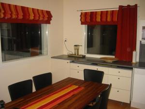 cocina con mesa de madera y cocina con cortinas rojas en Rattle Nest, en Loimaa