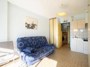 ein Wohnzimmer mit einem blauen Sofa und einer Küche in der Unterkunft Studio Floralies I-4 by Interhome in Le Grau-du-Roi