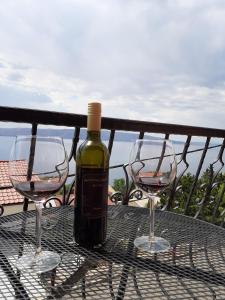 butelka wina na stole z dwoma kieliszkami wina w obiekcie Apartments & Room MaDi w mieście Senj