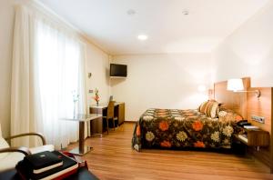 ムルシアにあるホテル エル チュラのベッドとデスクが備わるホテルルームです。