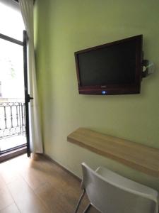 
a tv sitting on top of a wooden stand next to a window at BARCELONA GOTIC Guesthouse in Barcelona
