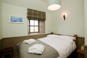 a bedroom with a bed with two towels on it at Balnakeil Beach Bothy in Durness