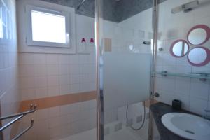 a bathroom with a glass shower and a sink at Appartement Proche plage in Le Grau-du-Roi