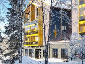 a building in the snow with trees in the foreground at Holiday Home Levin kunkku b8 by Interhome in Sirkka