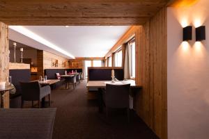 restauracja z drewnianymi ścianami, stołami i krzesłami w obiekcie Muntanella w Lech am Arlberg