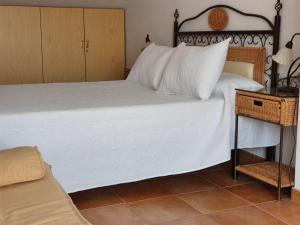 a bedroom with a large white bed and a night stand at Apartamentos Fuente La Raja in La Iruela