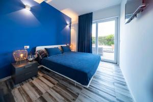 a blue bedroom with a bed and a large window at NelBlu in Polignano a Mare