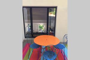 une table et des chaises orange devant une fenêtre dans l'établissement La Baraquette, à Sète
