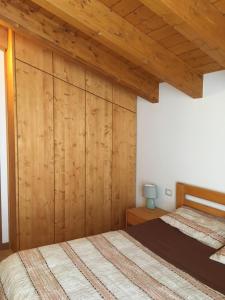 two beds in a bedroom with wooden walls at La vista sulla Valmalenco in Lanzada