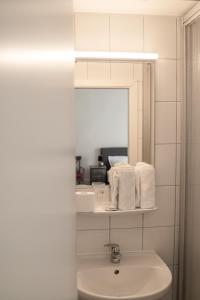Baño blanco con lavabo y espejo en The Dubliner Hotel & Irish Pub en Heidelberg
