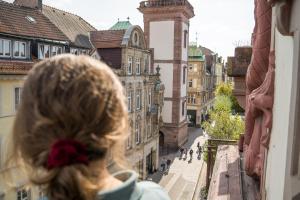 Eine Frau, die aus einem Fenster in eine Stadtstraße schaut. in der Unterkunft The Dubliner Hotel & Irish Pub in Heidelberg
