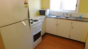 a small kitchen with a stove and a microwave at Cottage 53 - Topspot Cottages in Jurien Bay