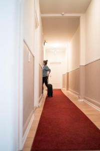 a man with a suitcase walking down a hallway with a red carpet at The Dubliner Hotel & Irish Pub in Heidelberg