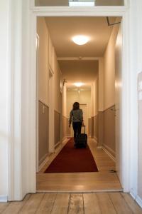 a woman walking down a hallway with a suitcase at The Dubliner Hotel & Irish Pub in Heidelberg