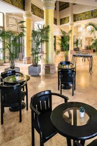 a lobby with tables and chairs and potted plants at Hotel Blue Weiss in Netanya