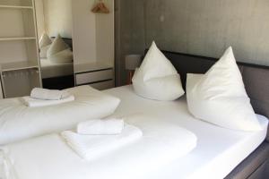 1 cama blanca con almohadas blancas y espejo en Apartment Monolith Black Forest, en Schonach