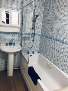 een badkamer met een bad, een wastafel en een douche bij The Cottage in Redruth