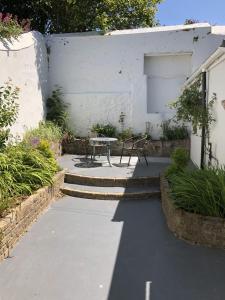 een patio met een tafel en een bank in een tuin bij The Cottage in Redruth