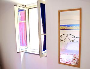 lustro na ścianie obok dwóch okien w obiekcie Il Borghetto Apartments & Rooms w mieście Procida