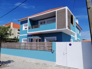 une maison bleue avec une clôture blanche devant elle dans l'établissement Lisbon Beach Apartments 6, à Costa da Caparica