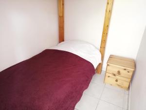um pequeno quarto com uma cama e uma mesa de cabeceira em madeira em Le MAELY, studio au calme, centre de Honfleur (linge fourni) em Honfleur