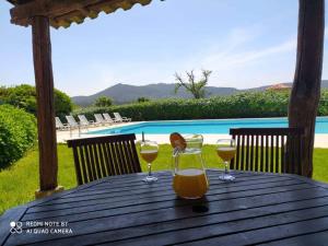 dos vasos de zumo de naranja en una mesa de madera junto a una piscina en Casa de Sta Comba, en Barcelos